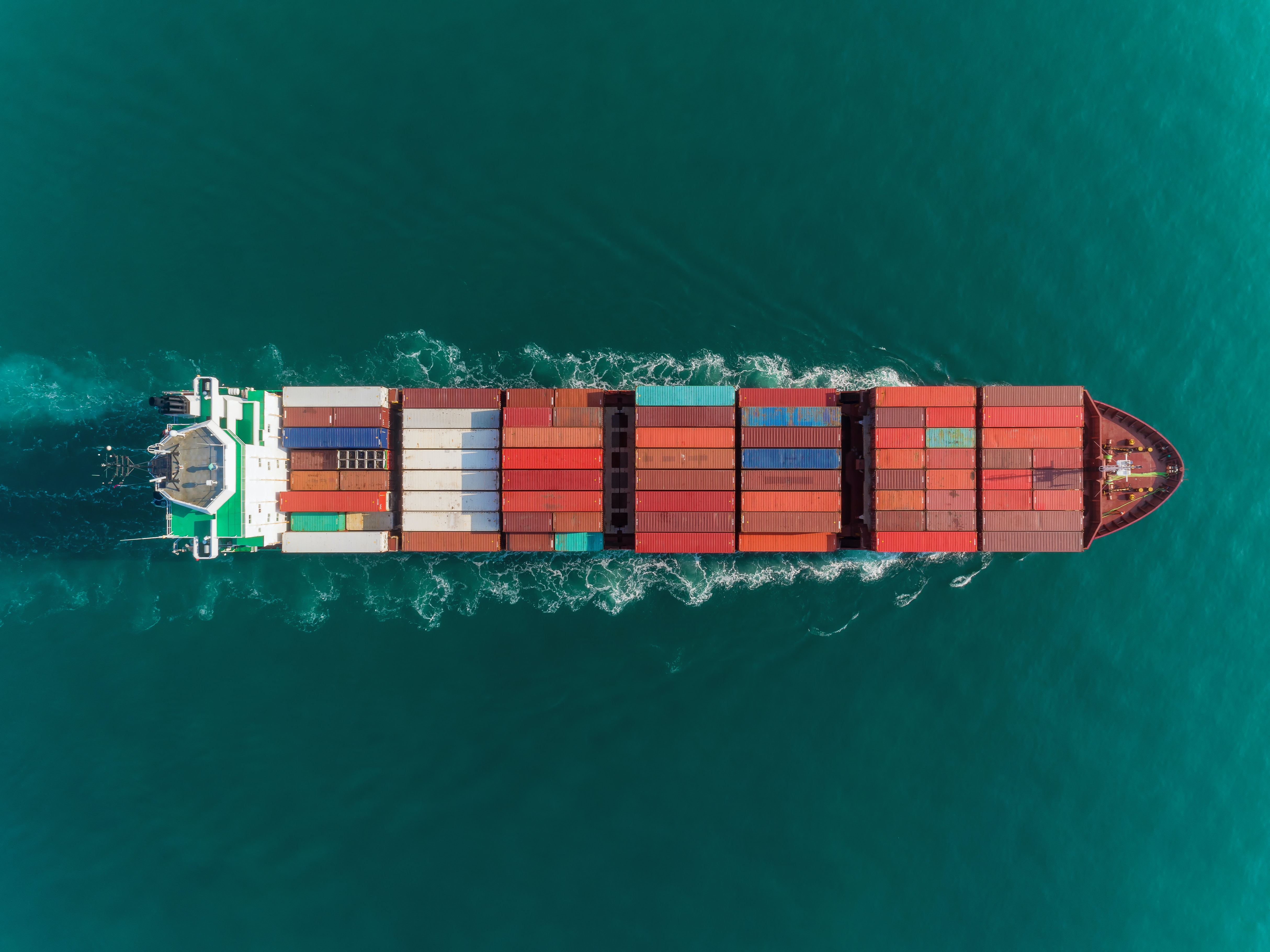 A birds-eye view of a container ship moving across the ocean